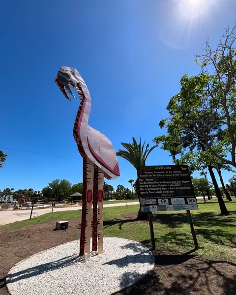 Escultura gigante de un flamenco junto a un cartel informativo en un parque de Miramar de Ansenuza