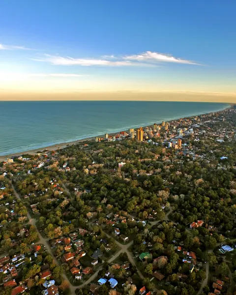 Vista aérea de Villa Gesell con el bosque que rodea las casas y la costa del mar al fondo